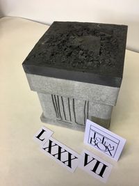 designurn beton met zwarte deksle en relief op voorzijde